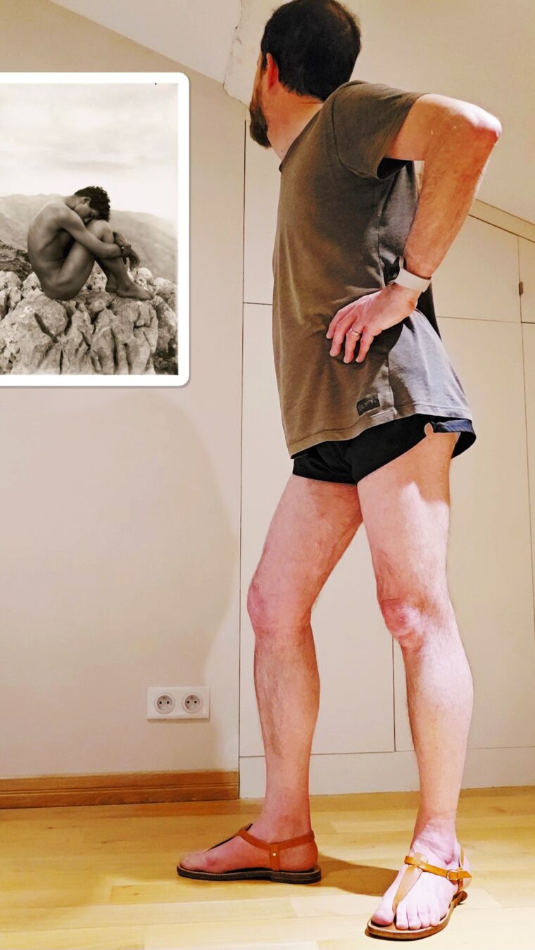 Homme en short regardant une photo de Wilhelm von Gloeden (1856-1931), "Portrait d'un homme nu sur les rochers", circa 1902.