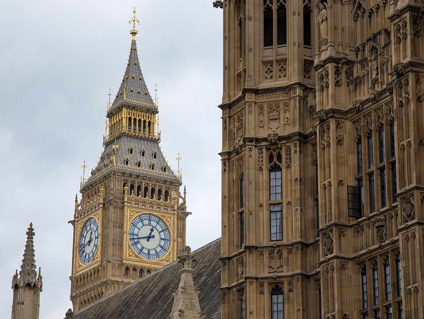 La Elizabeth Tower (Big Ben) en arrière plan, un détail de la façade du palais de Westminster au premier plan.