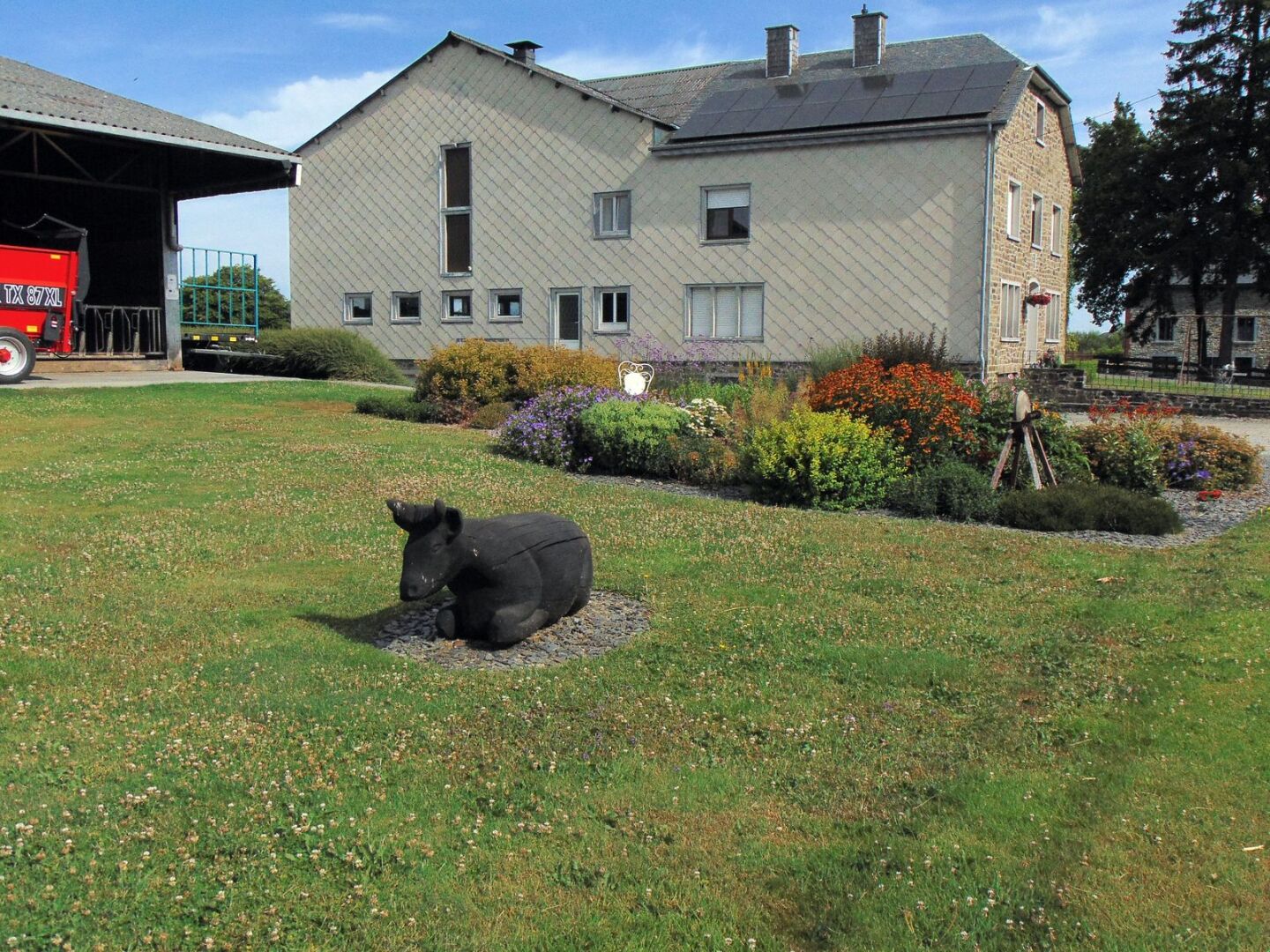 Une ferme dont le parterre est décoré d'une vache en bois et joliment fleuri