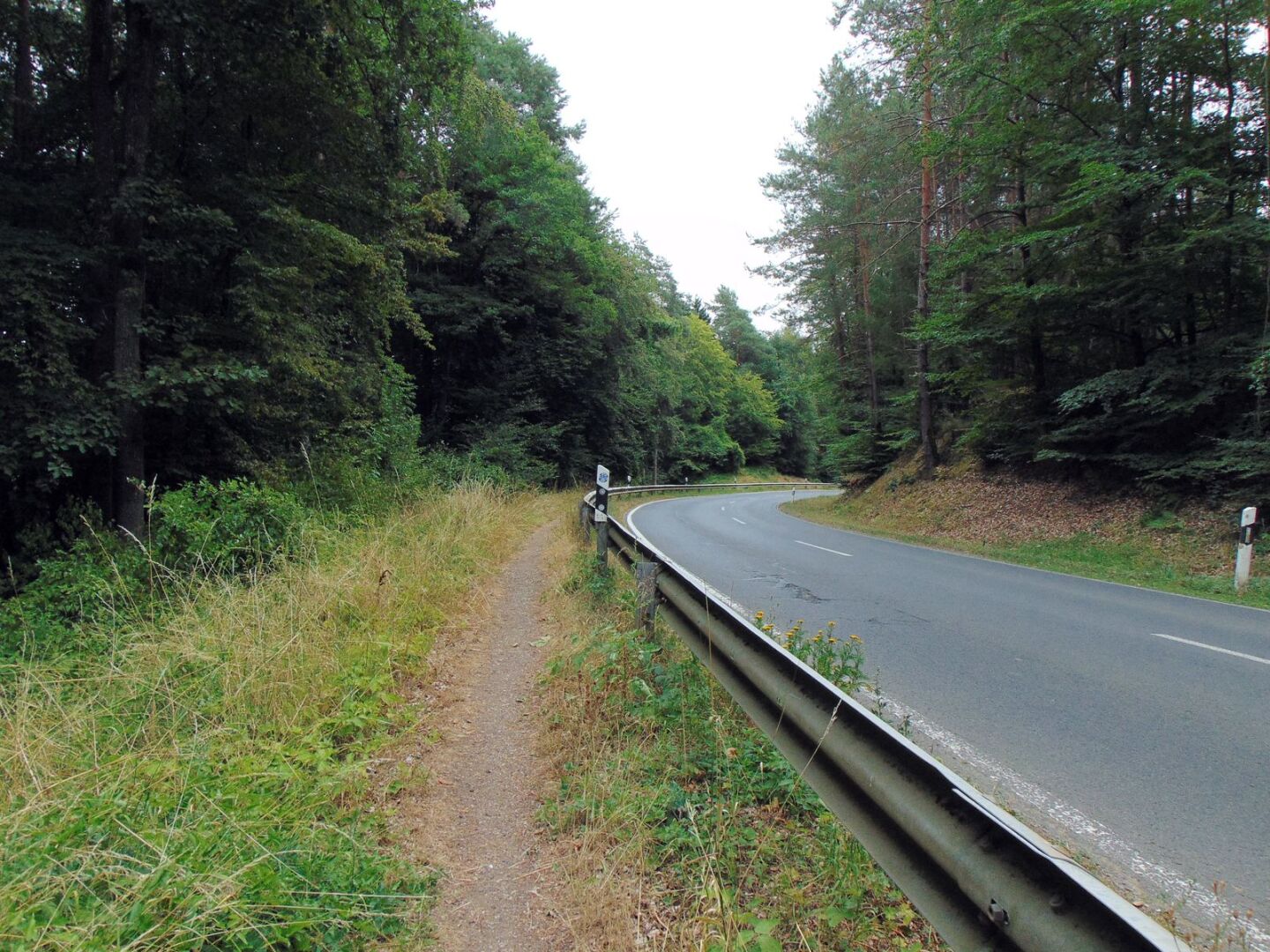 Un sentier le long d'une route avec des barrières de protection.